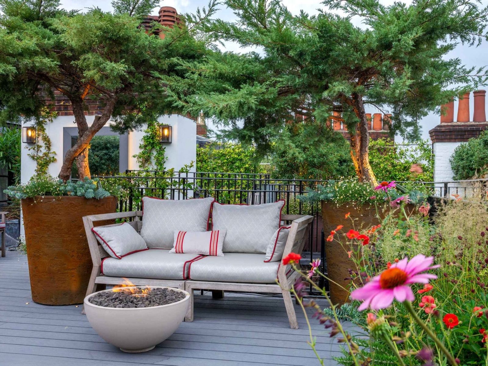 A decked seating area with an outdoor sofa and planting