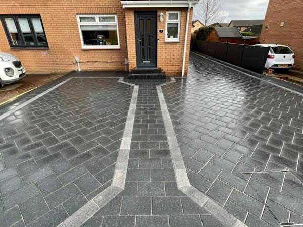 A charcoal block paved driveway with a light border